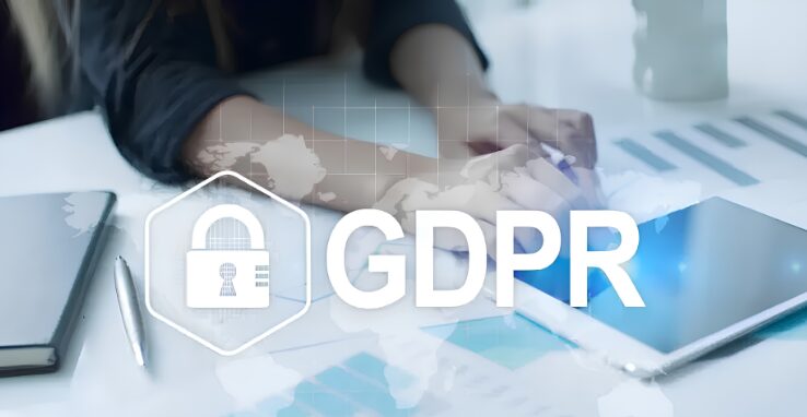 GDPR padlock icon over a person working at a desk with data reports and tablet
